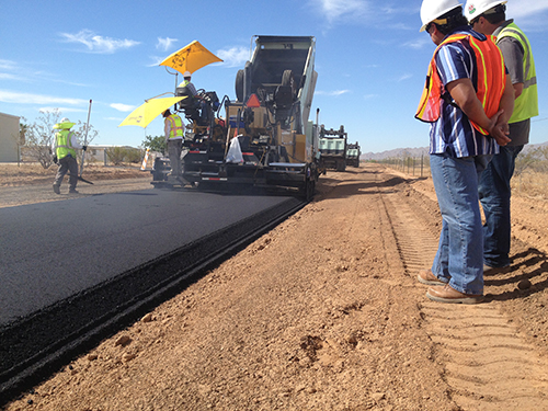 Photograph of a paving crew laying down a coat of asphalt