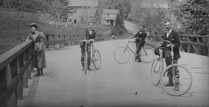 three men with bicycles on a bridge