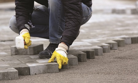 a worker laying paving bricks