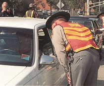 a police officer leaning in to talk to the driver of a car