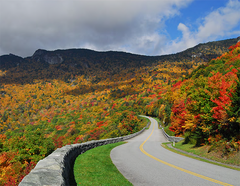 a windy road through colorful autumnal forest-covered hills